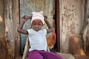 village small african girl seated on a wooden chair in her yard in a rural area